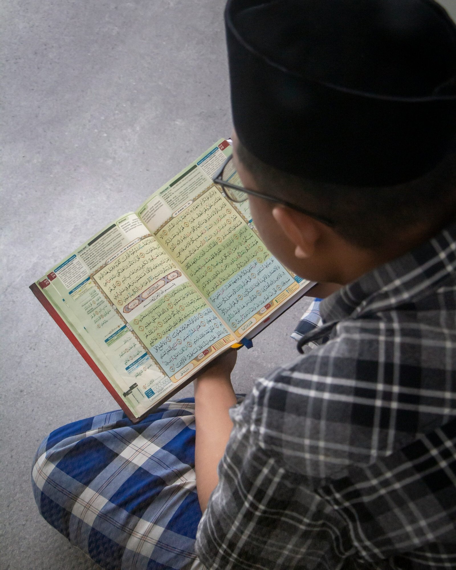 a young boy sitting on the floor reading a book